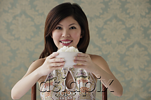 AsiaPix - Young woman raising bowl of rice smiling at camera