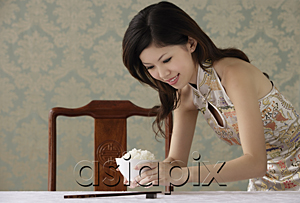 AsiaPix - Young woman placing bowl of rice on table