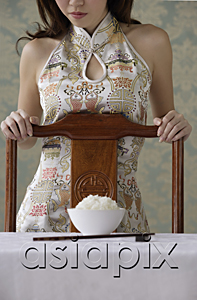 AsiaPix - Young woman behind chair with bowl of rice on table