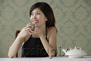AsiaPix - Young woman holding teacup looking sideway