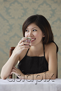 AsiaPix - Young woman drinking tea looking sideway