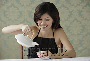 AsiaPix - Young woman sitting pouring tea