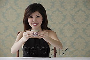 AsiaPix - Young woman holding teacup with both hands