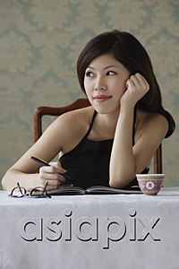 AsiaPix - Young woman with journal staring thoughtfully into distance