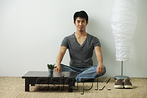 AsiaPix - Young man sitting on floor, looking at camera