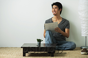 AsiaPix - Young man sitting on floor while writing