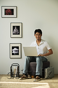 AsiaPix - Young man with laptop on lap looking at camera