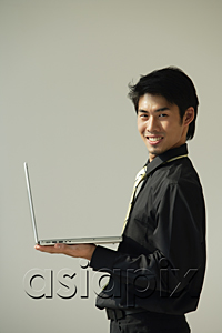 AsiaPix - Young man with laptop on one hand smiling at camera