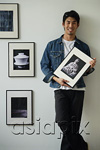 AsiaPix - Young man holding framed photographs