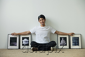 AsiaPix - Young man sitting on floor surrounded by framed photographs