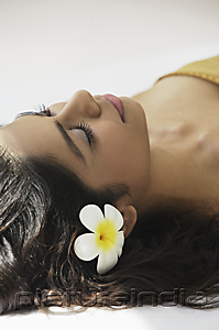 PictureIndia - A woman lying down with frangipani flowers around her