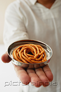 PictureIndia - A man holds out a dish of muruku