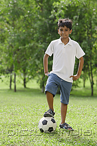 PictureIndia - A young boy looks at the camera as he rests his foot on a soccerball