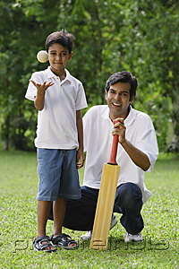PictureIndia - A father and son look at the camera as they play cricket together