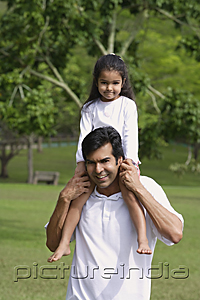 PictureIndia - A father carries his daughter on his shoulders as they both look at the camera