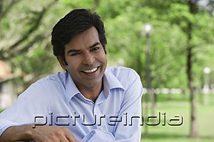 PictureIndia - A man smiles at the camera as he sits in the park