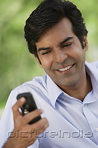 PictureIndia - A man smiles as he checks his cellphone