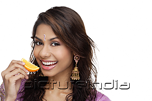 PictureIndia - A young woman smiles at the camera as she eats a slice of orange