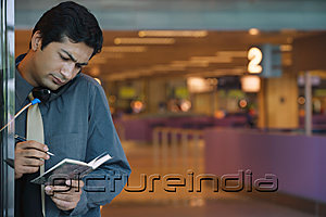 PictureIndia - Man making notes while on the phone
