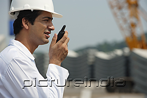 PictureIndia - Man in work uniform, talking into walkie talkie