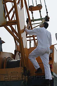 PictureIndia - Man in work uniform getting onto crane