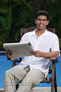 PictureIndia - Man sitting in chair holding a newspaper and looking at camera