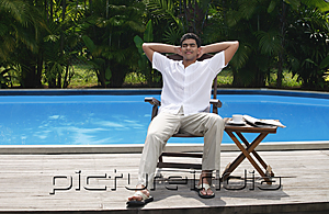 PictureIndia - Man relaxing in chair by the pool