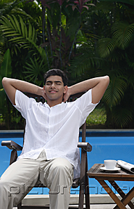 PictureIndia - Man relaxing in chair by the pool