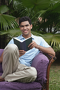 PictureIndia - Man with book on chair, smiling at camera