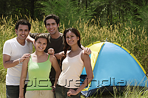 PictureIndia - Young friends camping in the wilderness, smiling at camera
