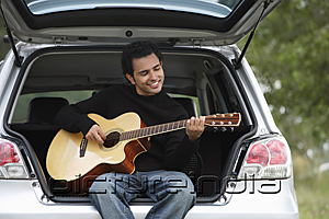 PictureIndia - Young man sitting car boot playing guitar
