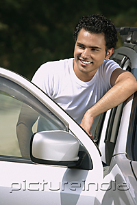 PictureIndia - Young man by car smiling into distance