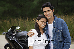 PictureIndia - Young couple with motorbike smiling at camera