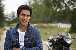 PictureIndia - Young man with motorbike smiling at camera