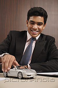 PictureIndia - Businessman playing with toy car