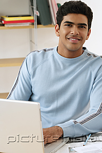 PictureIndia - Young man with laptop smiling at camera