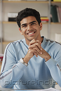 PictureIndia - Young man sitting at desk and smiling at camera
