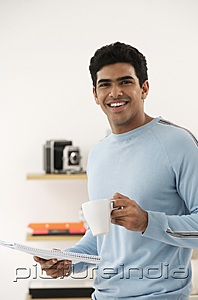 PictureIndia - Young man with coffee and paper smiling at camera